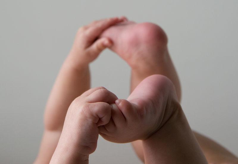 Baby holding feet, curling toes and fingers